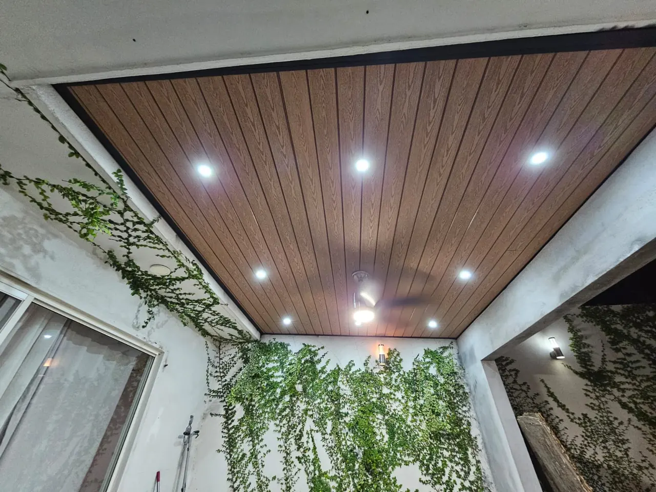 Techo de deck sintético con spots sobre un patio interior con enredaderas