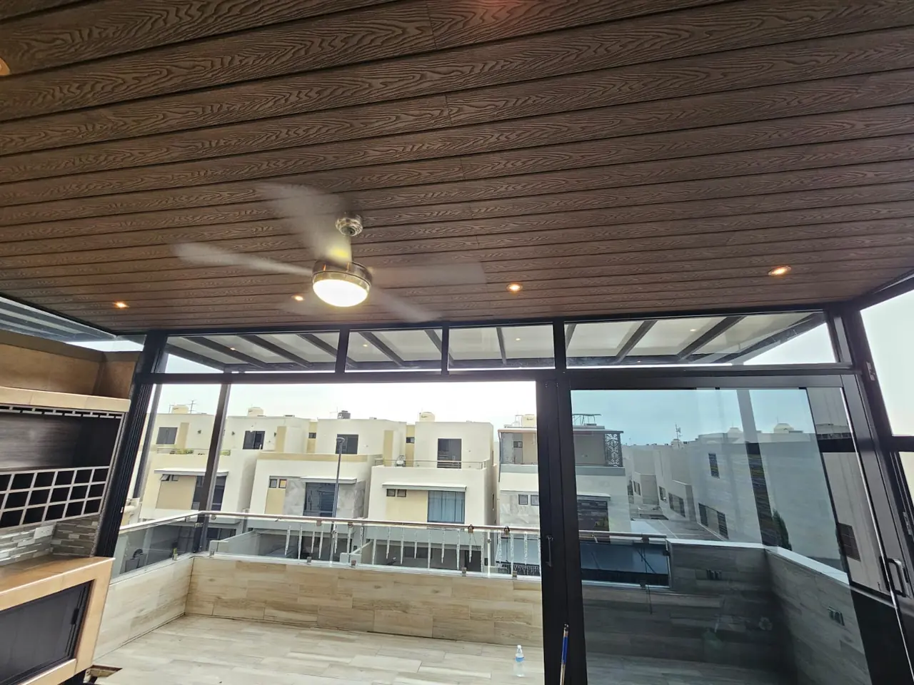 Techo con acabado de deck sintético, spots y ventilador sobre una terraza en planta alta