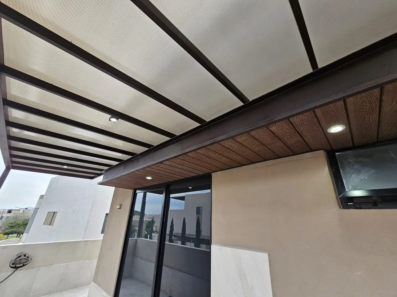 Vista de la pérgola de policarbonato y deck sintético con spots en la terraza