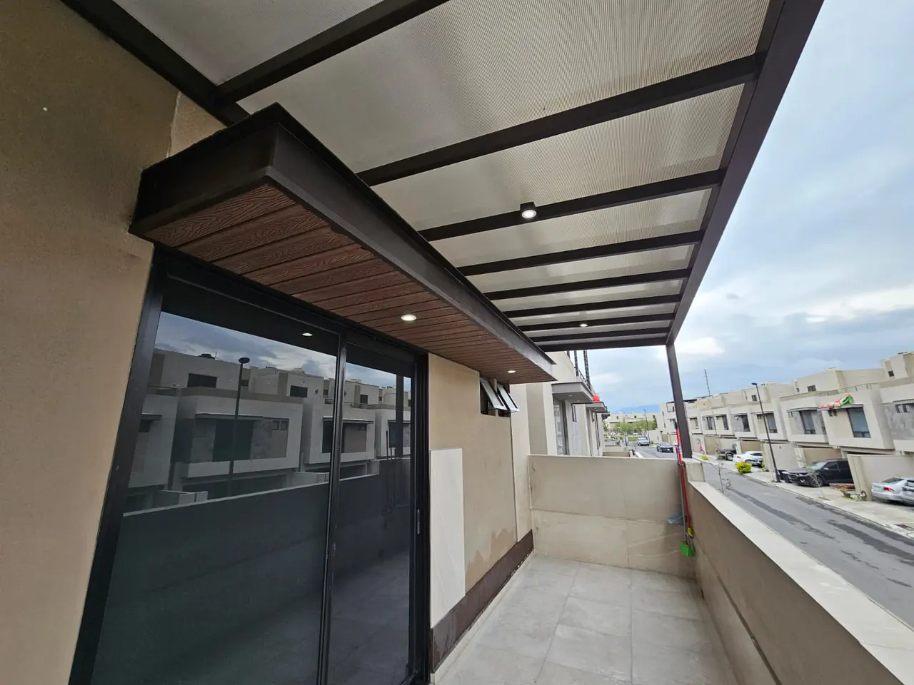 Pérgola de policarbonato con frente de deck sintético sobre una terraza en planta alta