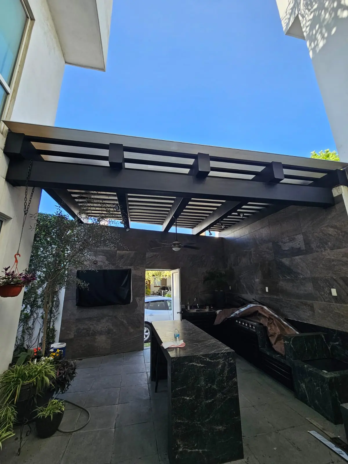 Techo de policarbonato sobre un patio con cocina exterior y barra