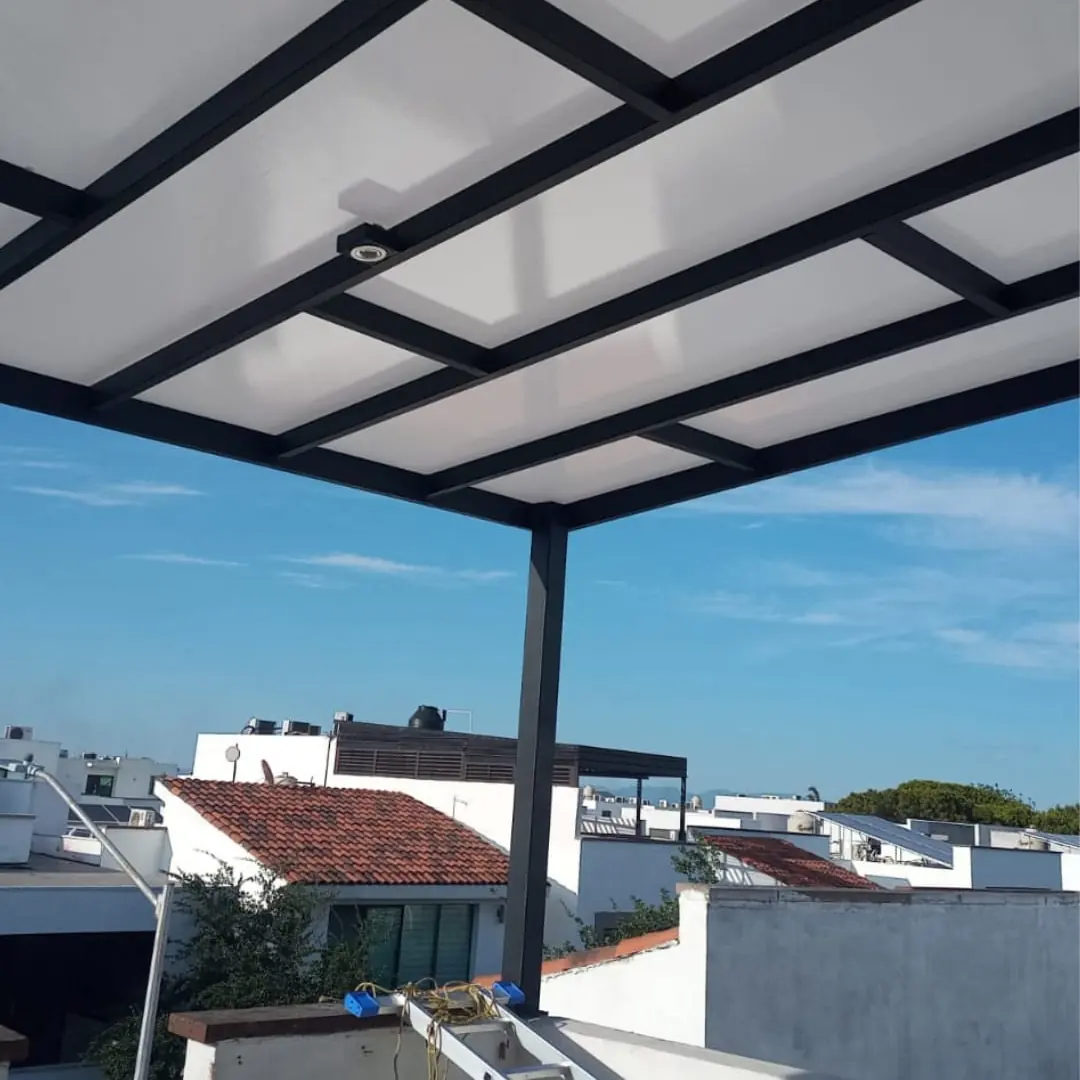 Techo de policarbonato con estructura metálica y spot sobre una terraza