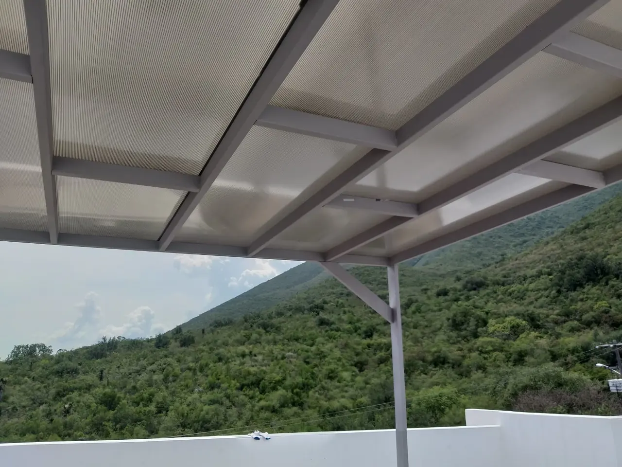 Techo de policarbonato con estructura metálica en una terraza con vista a la montaña