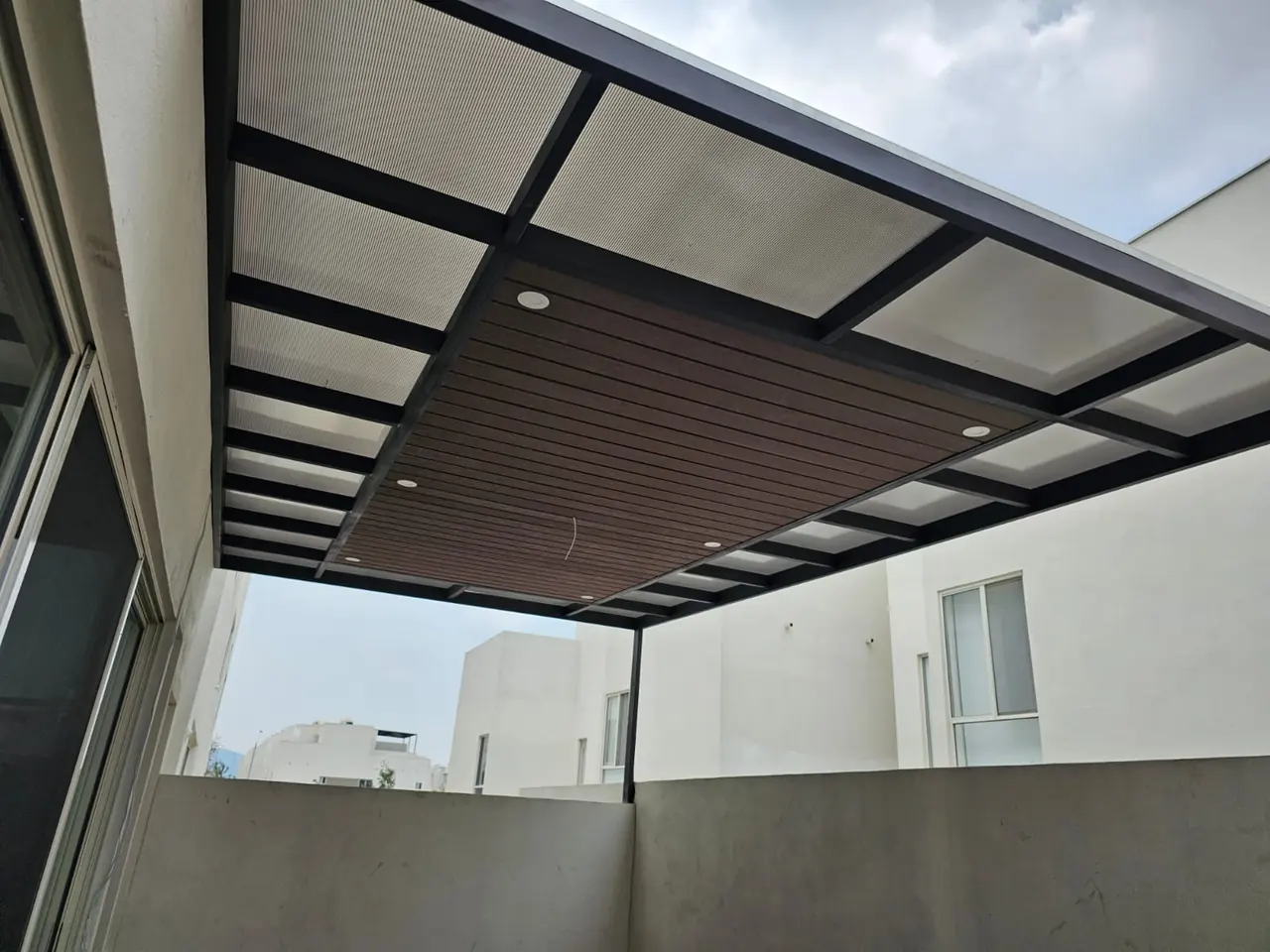 Terraza cubierta con policarbonato y sección de deck sintético