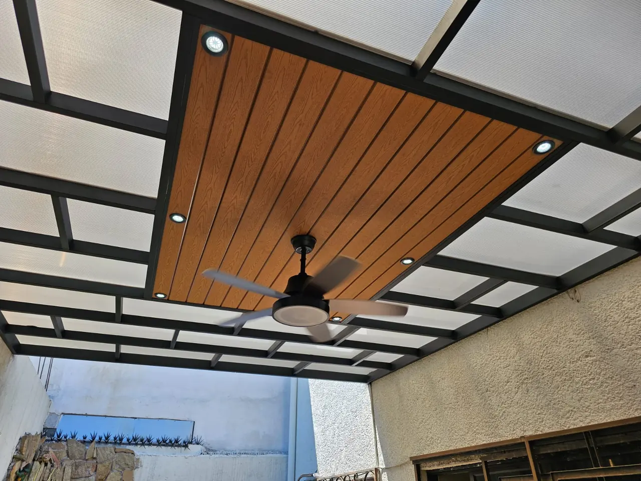 Techo con zona central de deck sintético, spots y ventilador, rodeada de policarbonato